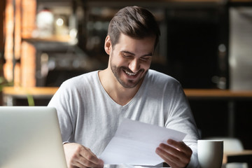 Satisfied millennial businessman reading paper letter with good news