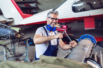 Aircraft mechanic repairs an aircraft engine 