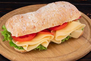 Ciabatta sandwich with lettuce , prosciutto and  cheese on wooden board