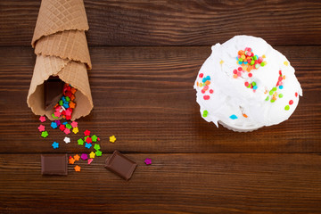 plate of vanilla ice cream scoop swith sprinkles and waffle cones on wooden background with copy space