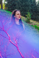 The young girl in a dress with a long skirt walks in the spring park. Blue a patch of light from a disk. Sunny weather. Fashion.