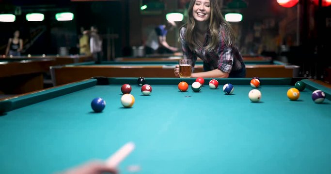 Beautiful smiling woman playing snooker in club