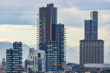 City skyline with skyscrapers of Porta Nuova district in Milan, Italy, Europe. Mountains behind the tall buildings.