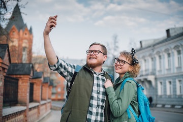 A young couple of newlyweds are walking around the big city, taking selfies.