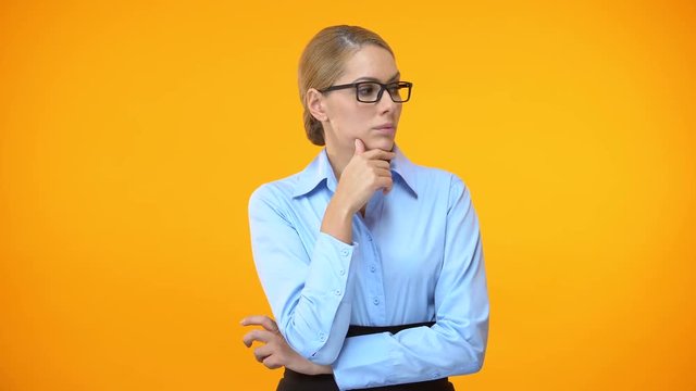 Thoughtful woman looking right and left on orange background, difficult choice