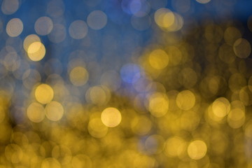 Obraz premium A lot of large golden bokeh bubbles from night city decorations on a soft blue background
