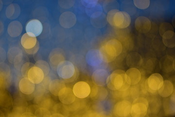 Obraz premium A lot of large gold, blue and white bokeh bubbles from the night city decorations on a soft blue background
