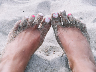 Legs with pink polish nail gel on the beach. sand on feet. summer vacation.