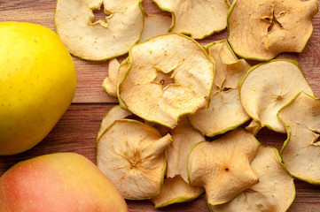 Healthy snack. Homemade dried apple chips and fresh apples on a rustic wooden background