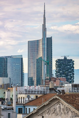 Fototapeta na wymiar Famous skyscrapers in the business district of Milan, Italy, Europe. Mountains seen behind the city skyline.