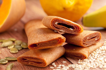 Homemade fruit leather of orange, orange, banana on a wooden background. Pastila. Fruit rolls. Fresh fruits