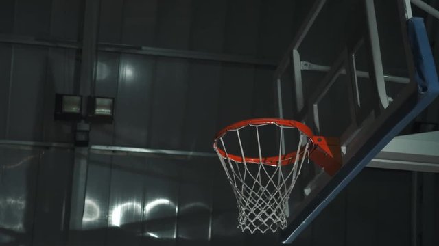 Basketball player makes a slam dunk during a game. He wears unbranded sport clothes.