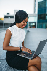 Business woman uses laptop against office building