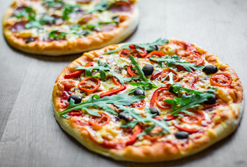 Pepperoni Pizza and Pizza with Mozzarella cheese, Tomatoes, pepper, olive, Spices and Fresh arugula. Pizza Margherita or Margarita on wooden table background