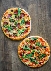 Pepperoni Pizza and Pizza with Mozzarella cheese, Tomatoes, pepper, olive, Spices and Fresh arugula. Pizza Margherita or Margarita on wooden table background