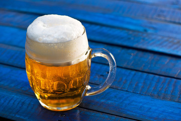 Glass of beer on the blue wooden background.