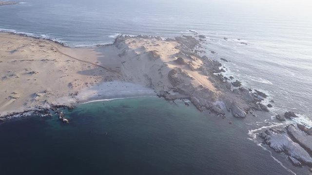 Las Tortolas beach aerial footage at Atacama Desert the sunset ray lights illuminate this amazing and idyllic beach in the middle of the desert, an arid awe landscape crashed by Pacific Ocean waters