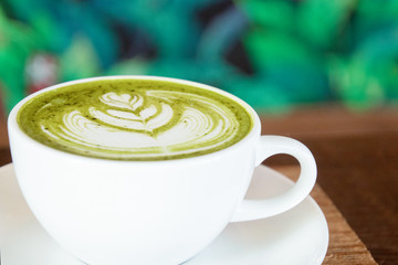 Coffee cup with Green Matcha latte art foam on wood table in coffee shop with copy space.Coffee is one of the most popular beverages.Improve Energy Levels and Burn Fat
