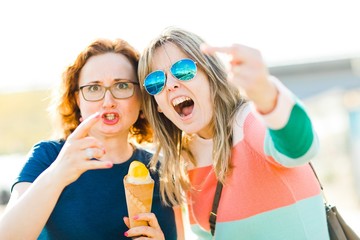 Two angry women showing obscene gestures.