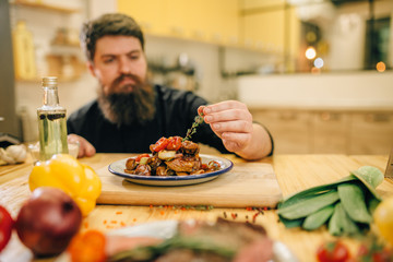 Chef decorates with herbs a meat dish for gourmets