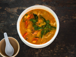Sour and spicy Tom Yum Goong soup on a table in a restaurant. Thai traditional food. Authentic traditional Thai soup Tom Yam on a wooden table