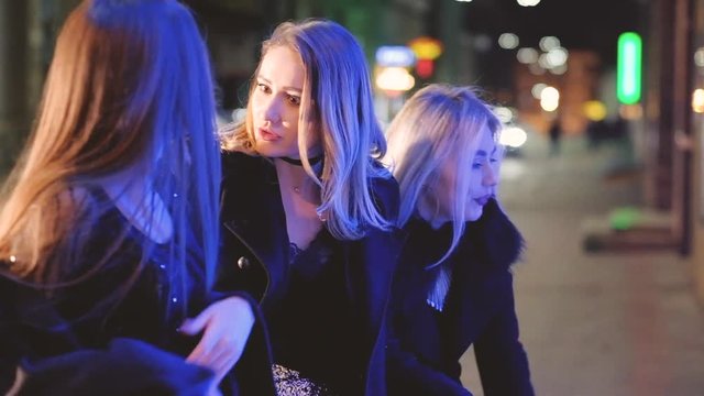 Girls night out. Ladies having fun, walking on the street, stopped to look at shop window, discussing new collection.