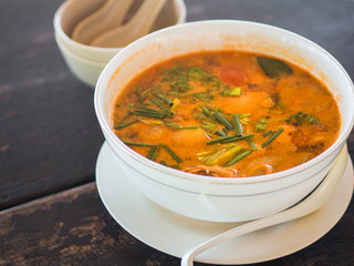 Sour and spicy Tom Yum Goong soup on a table in a restaurant. Thai traditional food. Authentic traditional Thai soup Tom Yam on a wooden table