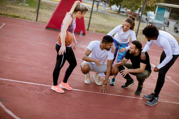 Fototapeta premium Multiethnic group of basketball players resting on court