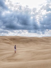 Looking out into the horizon and sand dunes whilst dark clouds linger overhead