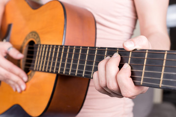 Obraz premium Closeup of young woman hand playing acoustic guitar. Teen girl learning to play song