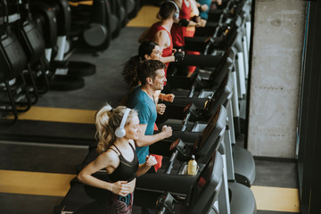 Above view at group of young people running on treadmills in modern sport gym