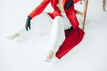 cropped view of stylish young woman sitting near wooden ladder on white