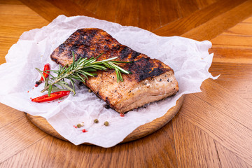 Grilled beef steaks with spices on wooden cutting board on wooden table.