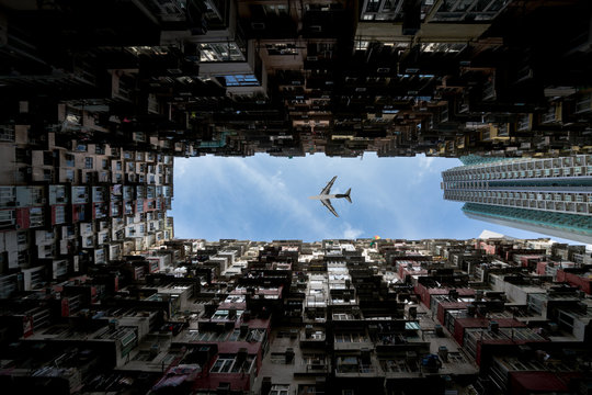 Hong Kong city residences area. Low angle view image of a crowded residential building in community with airplane flying over in Quarry Bay, Hong Kong