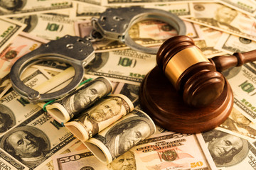 handcuffs, judge's hammer, American dollar bills. corruption, financial crimes.