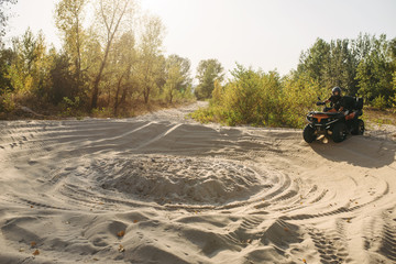 Fototapeta premium Atv rider in helmet climbing sandy road in forest