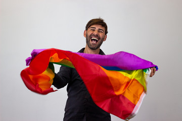 Portrait of handsome young man with gay pride movement LGBT Rainbow flag and brown hair looking...