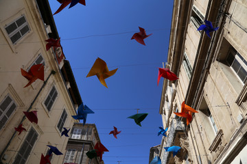 Bunte Windmühlen auf einer sonnigen Straße in Arles