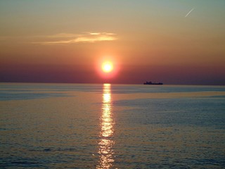 Genova, Italy - 03/15/2019: An amazing caption of the sunset in spring days over the sea of Genova with beautiful red and blue sky, some amazing clouds in the background and old rocks over the sea.