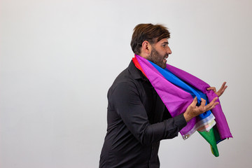 Portrait of handsome young man with gay pride movement LGBT Rainbow flag and brown hair looking...