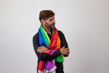 Portrait of handsome young man with gay pride movement LGBT Rainbow flag and brown hair grateful,...