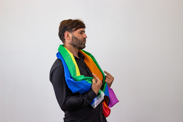 Portrait of handsome young man with gay pride movement LGBT Rainbow flag and brown hair showing nice face, facing forwards and looking at the side. Isolated on white background.