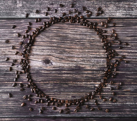Frame made of spilled coffee beans on a wooden table. Rustic stile.