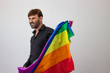 Portrait of handsome young man with gay pride movement LGBT Rainbow flag and brown hair excited, facing forwards and looking at the horizon. Isolated on white background.