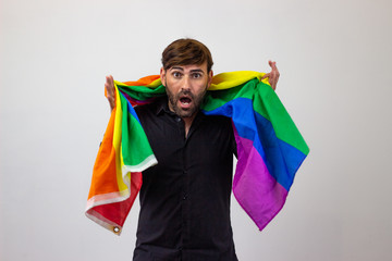 Portrait of handsome young man with gay pride movement LGBT Rainbow flag and brown hair quiet, looking at the camera. Isolated on white background.