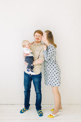 Photo shoot in the Studio, happy parents. Young family on a white background with the child.