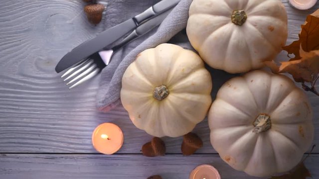 Thanksgiving holiday scene. Wooden table, decorated with pumpkins, autumn leaves and candles. Flatlay, Top view. 4K UHD video footage. 3840X2160