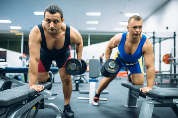 Naklejka na ściany i meble Two weightlifters doing exercise with dumbbells