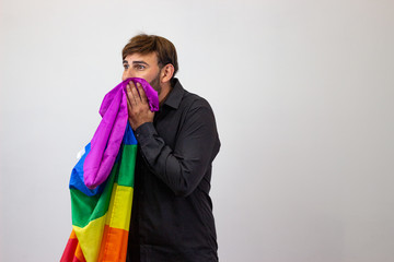 Portrait of handsome young man with gay pride movement LGBT Rainbow flag and brown hair stressed,...