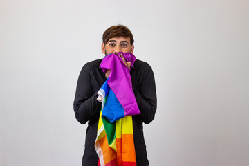 Portrait of handsome young man with gay pride movement LGBT Rainbow flag and brown hair stressed,...